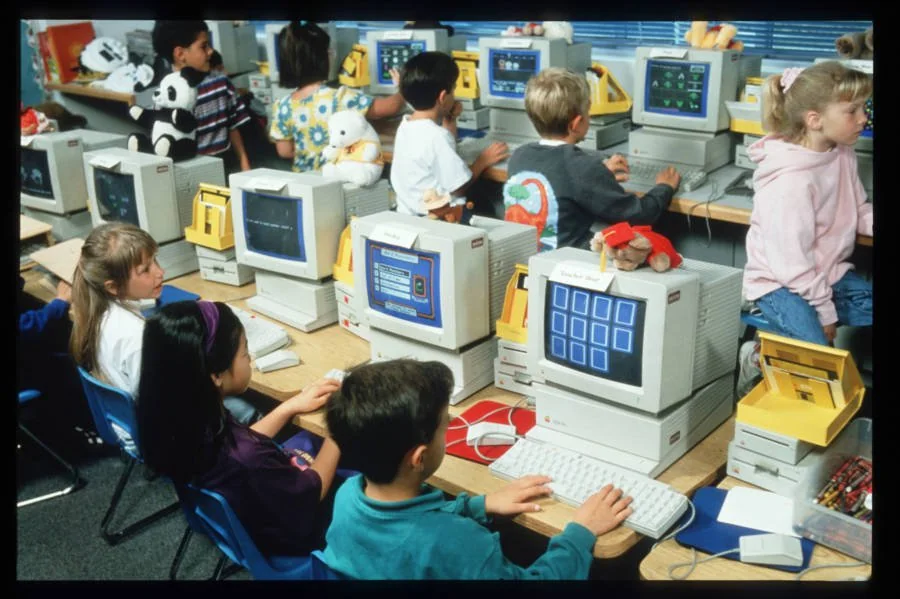 Vintage photograph of young children working in a computer lab.